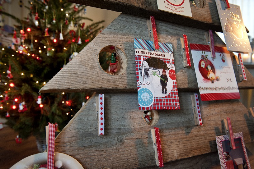 steigerhouten kaartenboom met kerstkaarten en op achtergrond kerstboom