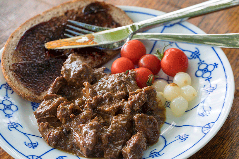 Bord met brood, zuurvlees, zilveruitjes en tomaatjes