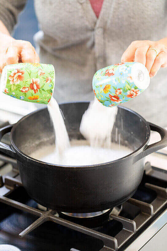 Twee kopjes met baking soda en zout worden aan vloeibare vloerreiniger toegevoegd