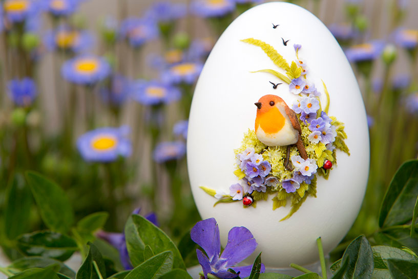 Ei versierd met bloemen en vogeltje van klei.