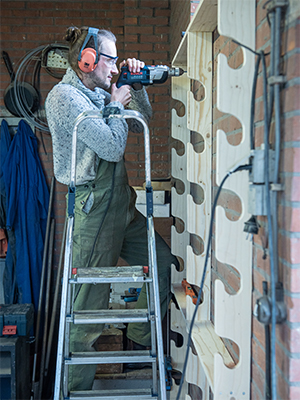 Man boort houten rek aan de muur