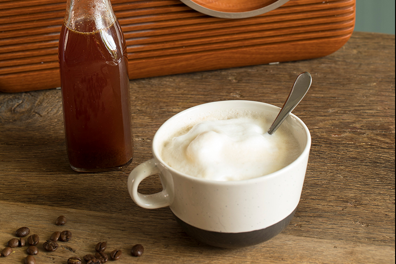 Een flesje siroop en een kopje koffie met melkschuim