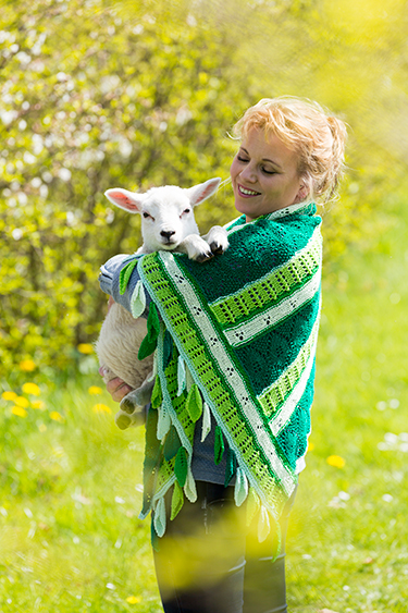 Vrouw met lammetje in de armen en vrolijke groene voorjaarsshawl om.